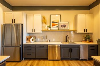 A kitchen with a stainless steel refrigerator and a sink with a faucet.